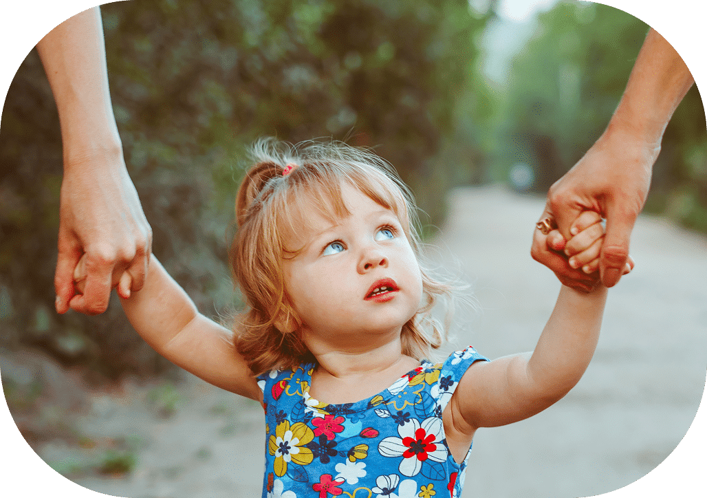 Nena petita caminant de la mà dels seus pares en un entorn natural, teràpia infantil PTI